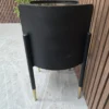 right side of the black curved retro side table with exposed legs which have gold tips