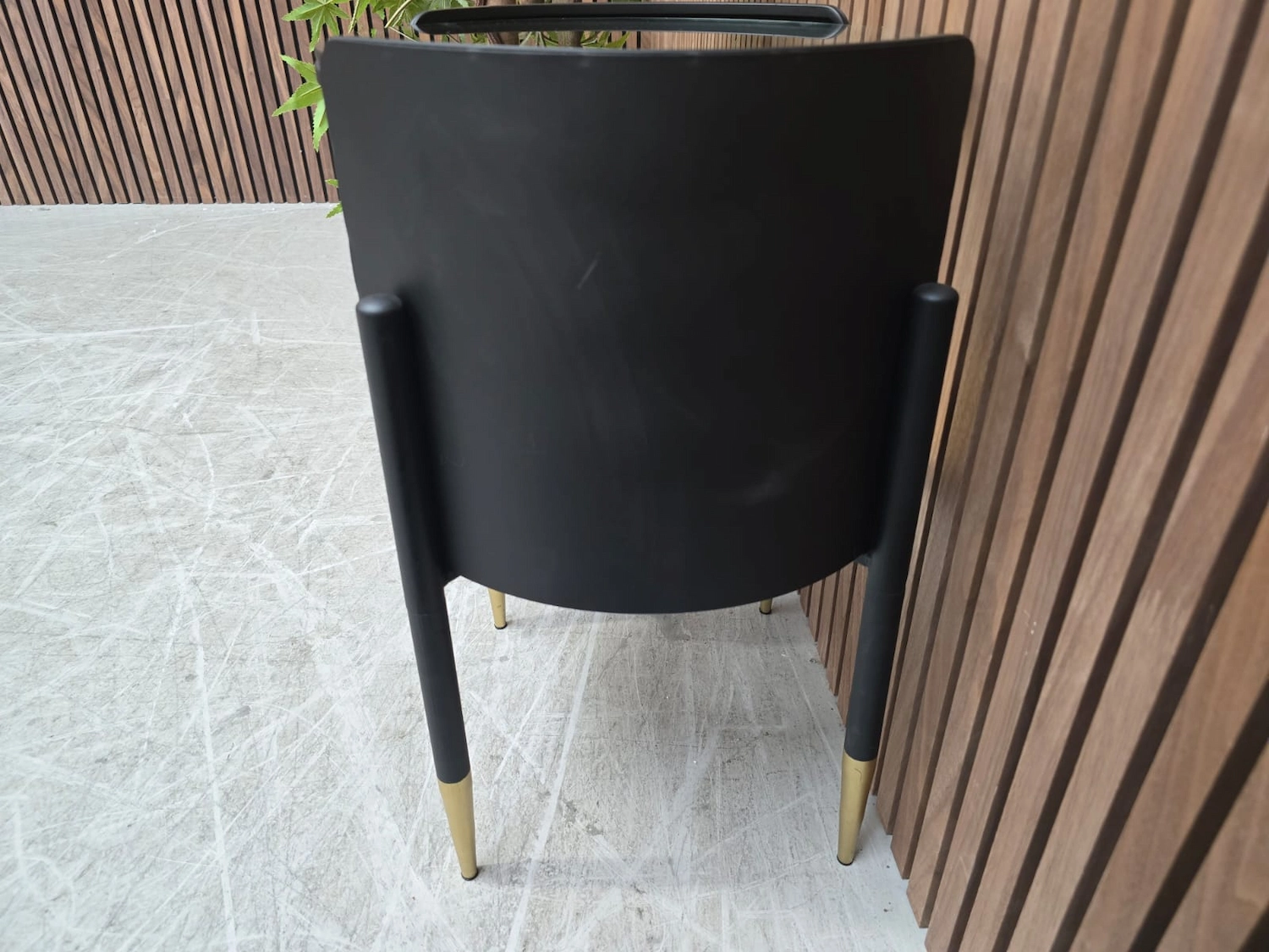 right side of the black curved retro side table with exposed legs which have gold tips