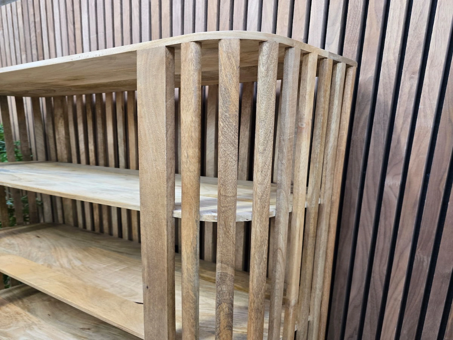 curved slatted mango wooden detail on the top of the bookshelf